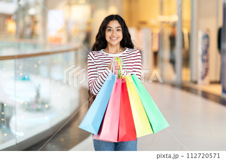 Smiling young indian woman buyer holding shopping bags Smiling young indian woman buyer holding shopping bags 112720571
