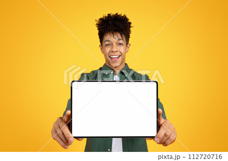 Positive african american guy showing tablet with white screen 112720716
