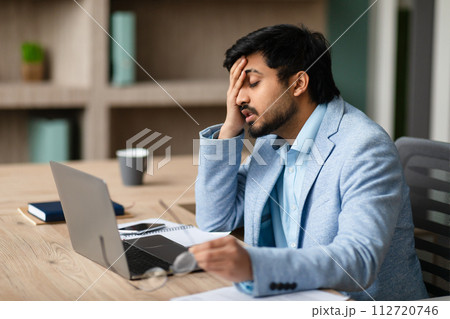 Exhausted Middle Eastern Businessman Touching Face Sitting At Laptop Indoor Exhausted Middle Eastern Businessman Touching Face Sitting At Laptop Indoor 112720746