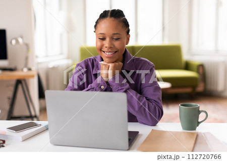 Smiling african american female student with laptop enjoying online learning 112720766