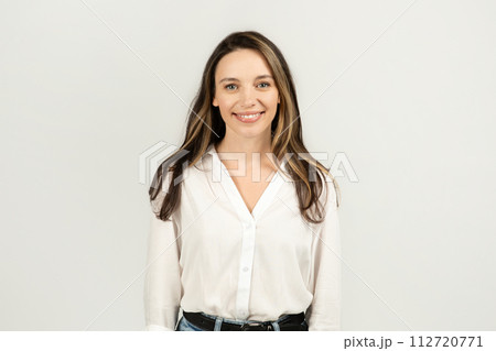 A friendly young woman with long brunette hair, wearing a crisp white blouse and blue jeans A friendly young woman with long brunette hair, wearing a crisp white blouse and blue jeans 112720771