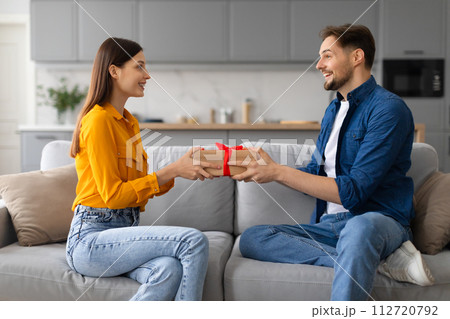 Happy spouses exchanging gifts, woman receiving present Happy spouses exchanging gifts, woman receiving present 112720792