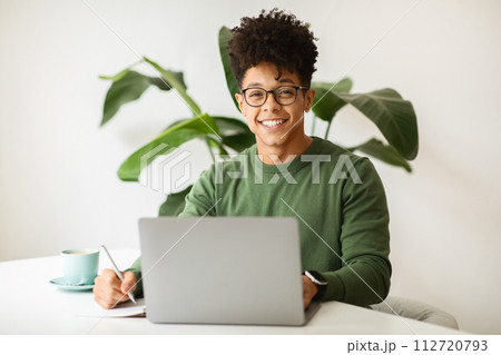Cheerful stylish black guy freelancer working at cozy cafe 112720793
