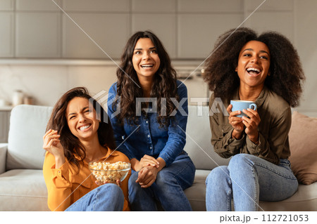Three international friends ladies gathers on sofa in living room 112721053