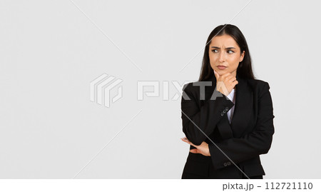 Thoughtful businesswoman in suit looking aside at free space Thoughtful businesswoman in suit looking aside at free space 112721110