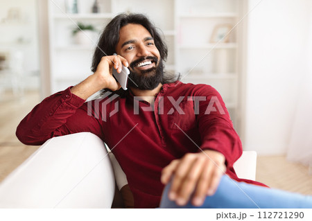 Closeup of cheerful indian guy have phone conversation at home 112721290