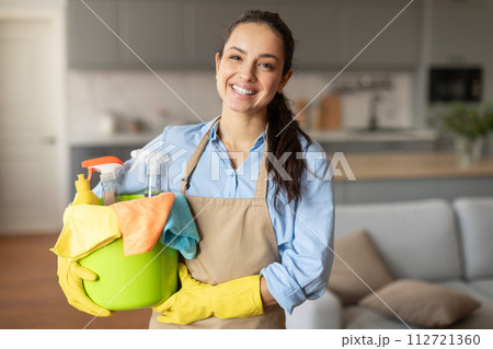Smiling woman ready with bucket of cleaning supplies Smiling woman ready with bucket of cleaning supplies 112721360
