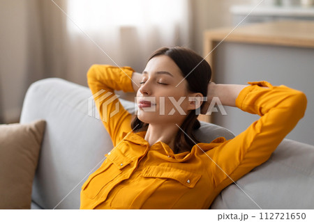Woman relaxing with eyes closed on comfortable sofa Woman relaxing with eyes closed on comfortable sofa 112721650