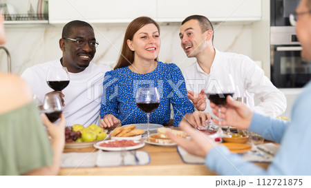 Happy adult friends at the festive table discussing news and drinking red wine Happy adult friends at the festive table discussing news and drinking red wine 112721875