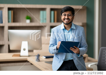 Happy Indian entrepreneur holds clipboard with signed document in office 112721892