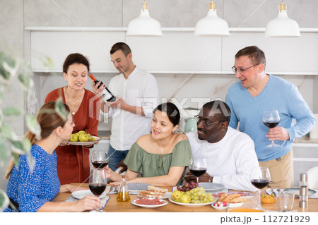 Happy adult friends at the festive table discussing news and drinking red wine Happy adult friends at the festive table discussing news and drinking red wine 112721929