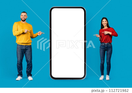 Place For Ad. Happy Young Caucasian Couple Pointing At Big Blank Smartphone 112721982