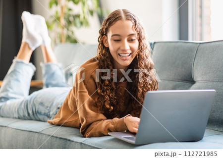 Happy modern adolescent girl enjoys e-learning with laptop at home 112721985