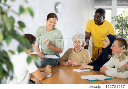 Group of multinational people discussing documents at table 112721987