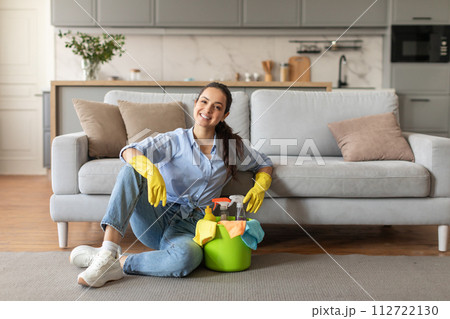 Relaxed woman sitting with her cleaning supplies at home 112722130