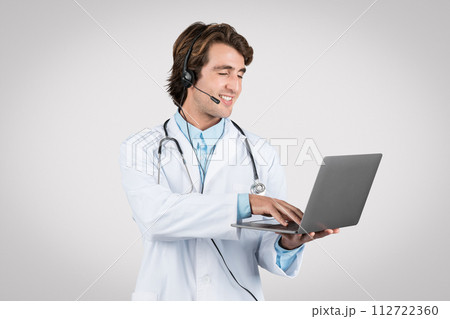 Smiling man doctor with headset using laptop for telehealth services Smiling man doctor with headset using laptop for telehealth services 112722360