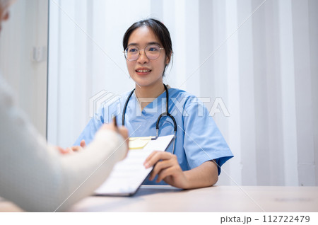 A doctor explaining a medical insurance claim document to a patient during a meeting in the office. A doctor explaining a medical insurance claim document to a patient during a meeting in the office. 112722479