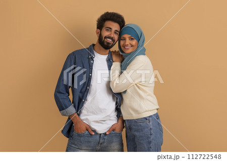 Portrait of romantic smiling muslim couple posing on beige studio background Portrait of romantic smiling muslim couple posing on beige studio background 112722548