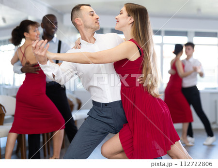 Young man and girl dancing tango in couple during lesson at studio Young man and girl dancing tango in couple during lesson at studio 112722806