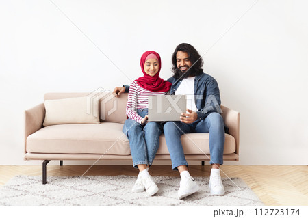 Portrait Of Romantic Muslim Spouses Relaxing With Laptop At Home 112723174
