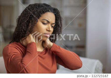 Young Black Female Suffering Neck Pain While Sitting On Couch At Home Young Black Female Suffering Neck Pain While Sitting On Couch At Home 112723187