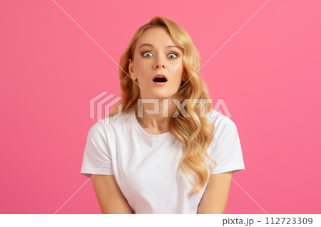 Shocked millennial blonde woman opening her mouth over pink background 112723309