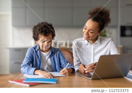 Black mother helps her son with homework at kitchen table 112723373