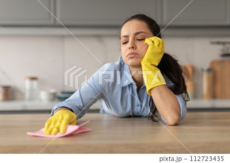 Tired young woman cleaning kitchen countertop 112723435
