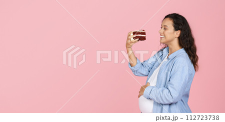 Glad millennial pregnant woman holding piece of cake Glad millennial pregnant woman holding piece of cake 112723738
