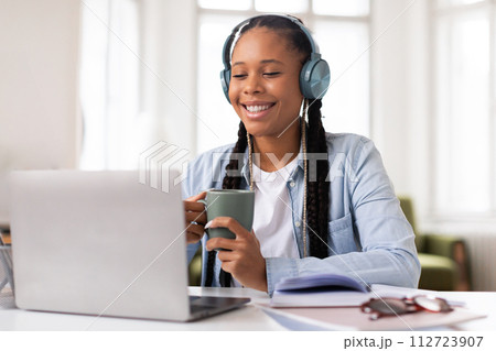 Smiling black female student with headphones studying at laptop 112723907