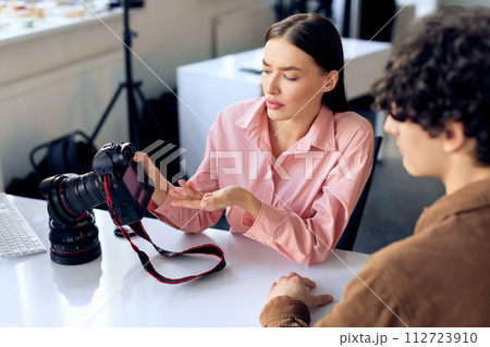Model discussing photo results with female photographer in studio setting Model discussing photo results with female photographer in studio setting 112723910