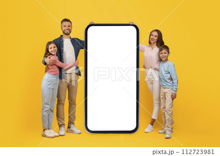 Happy Family Of Four Standing Near Big Smartphone With Blank Screen 112723981
