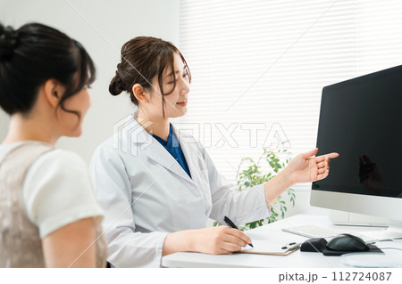 病院・クリニックでパソコンを使って診察・診療・説明・問診をする医師・医者の女性と患者 112724087