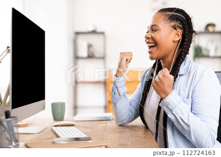 Excited student lady celebrating success in front of computer Excited student lady celebrating success in front of computer 112724163
