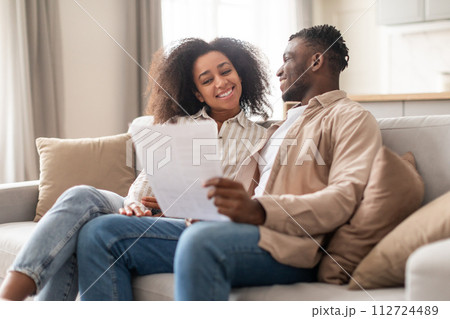 Happy black millennial couple managing paperwork together at home Happy black millennial couple managing paperwork together at home 112724489