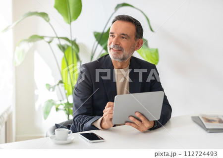 Optimistic mature businessman with a tablet in hand and a joyful expression 112724493