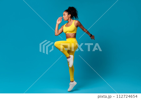 African American sportswoman doing elbow to knee standing pose, studio 112724654