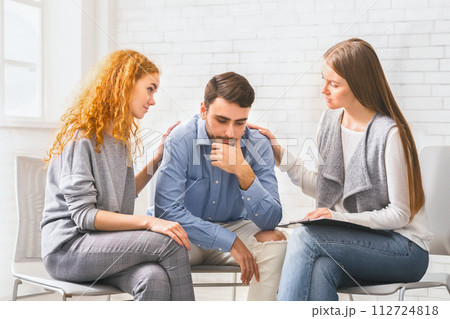 People comforting depressed addict man at rehab group meeting People comforting depressed addict man at rehab group meeting 112724818