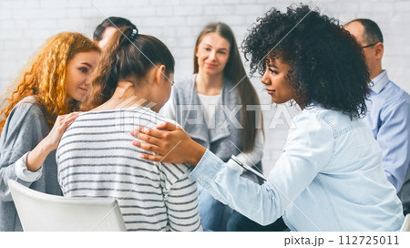 Addicted people comforting woman at psychotherapy session 112725011