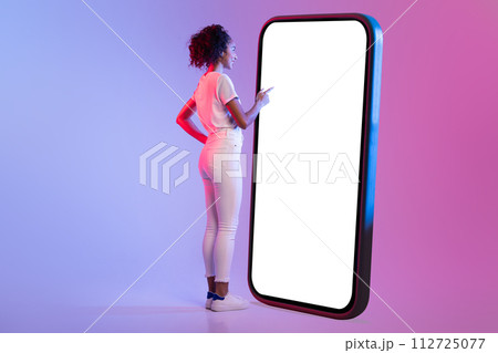 Woman interacts with giant smartphone on pink and blue background 112725077