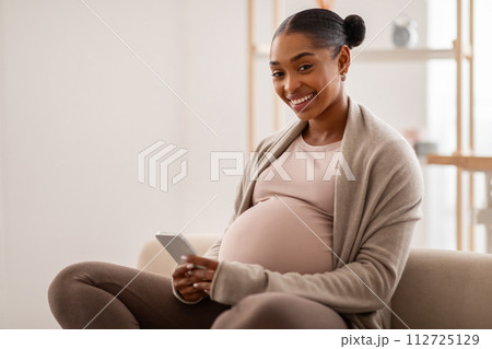 Cheerful happy african american pregnant lady using cell phone Cheerful happy african american pregnant lady using cell phone 112725129