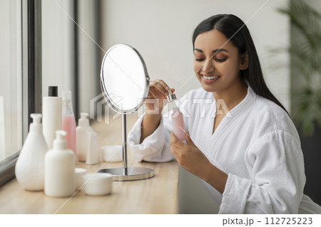 Beautiful young indian woman using face serum for glowing skin Beautiful young indian woman using face serum for glowing skin 112725223