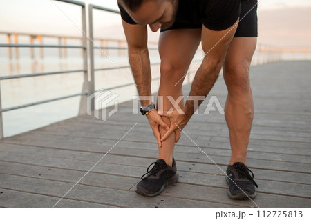 Runner guy having leg injury outside pressing shin in pain Runner guy having leg injury outside pressing shin in pain 112725813
