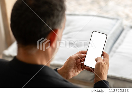 Over-the-shoulder view of a senior businessman in a dark blazer attentively 112725838