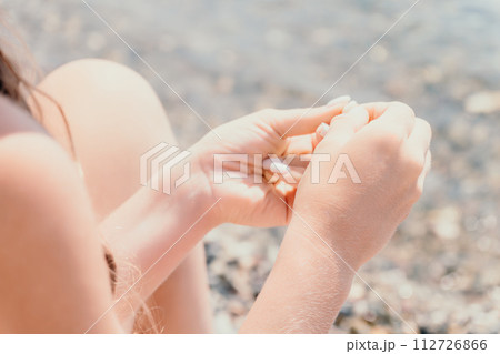 Woman eating milky almond nuts. A young caucasian woman chopping fresh green almond after morning fitness yoga near sea. Only hands are visibly. Healthy vegan food. Slow motion. Close up 112726866