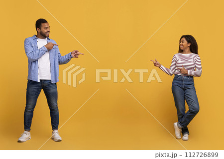 Black couple pointing at copy space in the middle of yellow background 112726899