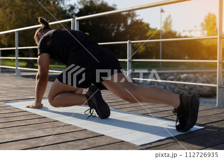Sporty man having outdoor workout doing elbow to knee plank 112726935