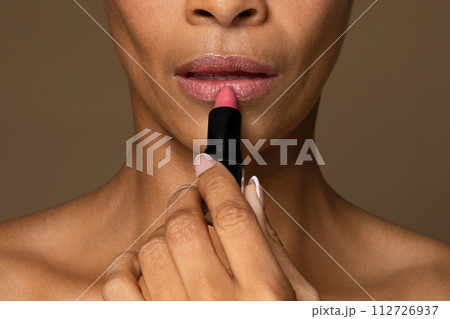Black woman applying pink lipstick, beauty close-up Black woman applying pink lipstick, beauty close-up 112726937