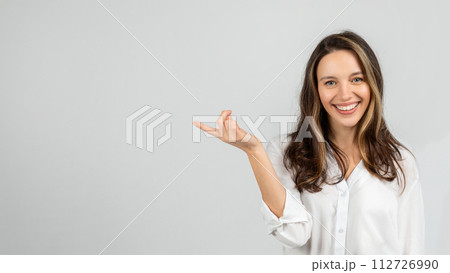 A happy young woman with a charming smile gestures with her hand as if holding something A happy young woman with a charming smile gestures with her hand as if holding something 112726990