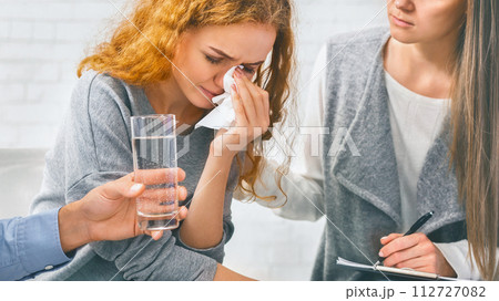 Depressed woman crying at support meeting, therapist comforting her Depressed woman crying at support meeting, therapist comforting her 112727082